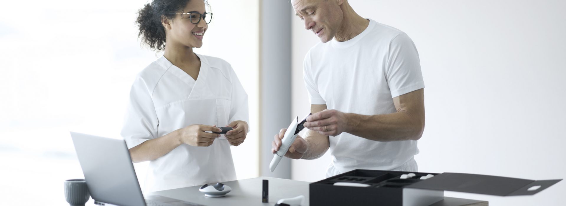 Aufnahme von einem Mann und einer Frau, der Mann hält das Akku und den Intraoralscanner in der Hand